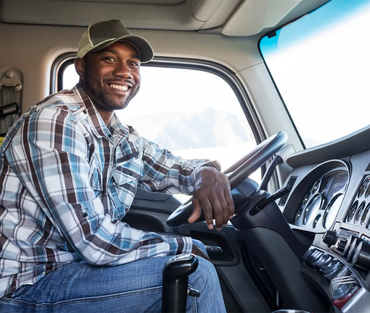 Man with a cap in front of a steering wheel of a truck